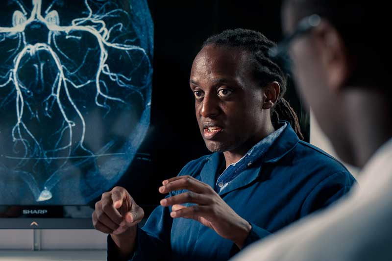 Clinical anatomy students and staff next to an MRI scan of a brain on a screen