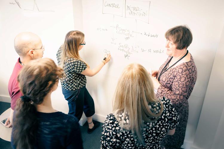 Researchers from Wolfson Palliative Care Research Centre working around a whiteboard
