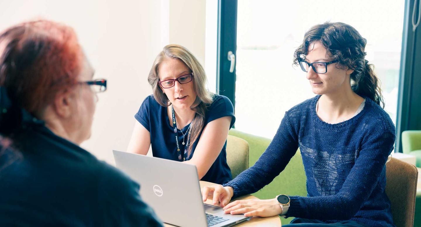 Researchers working around a laptop in Wolfson Palliative Care Research Centre
