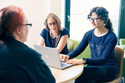 Researchers working around a laptop in Wolfson Palliative Care Research Centre