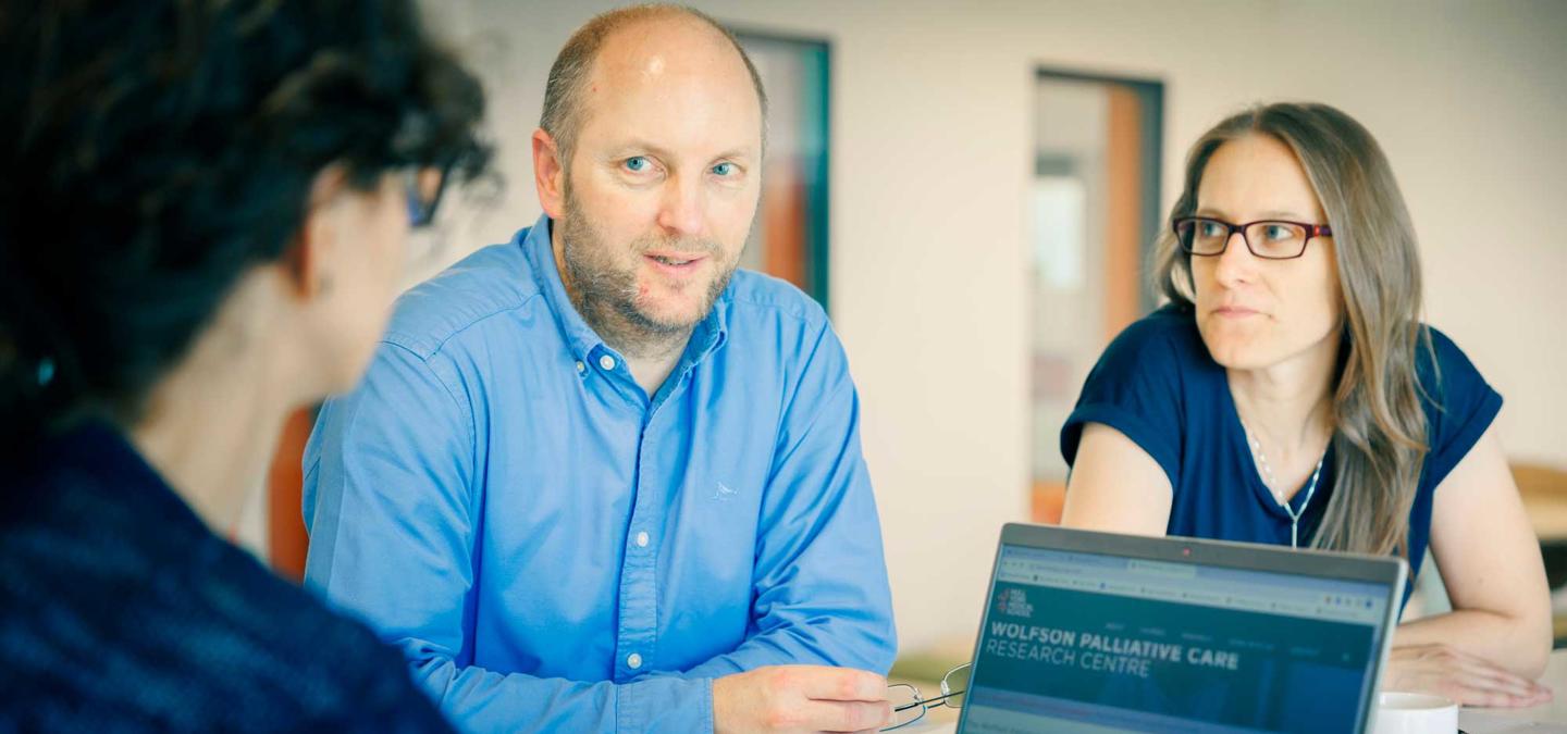 Researchers working around a laptop in Wolfson Palliative Care Research Centre