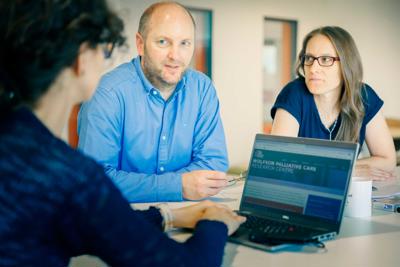 Researchers working around a laptop in Wolfson Palliative Care Research Centre