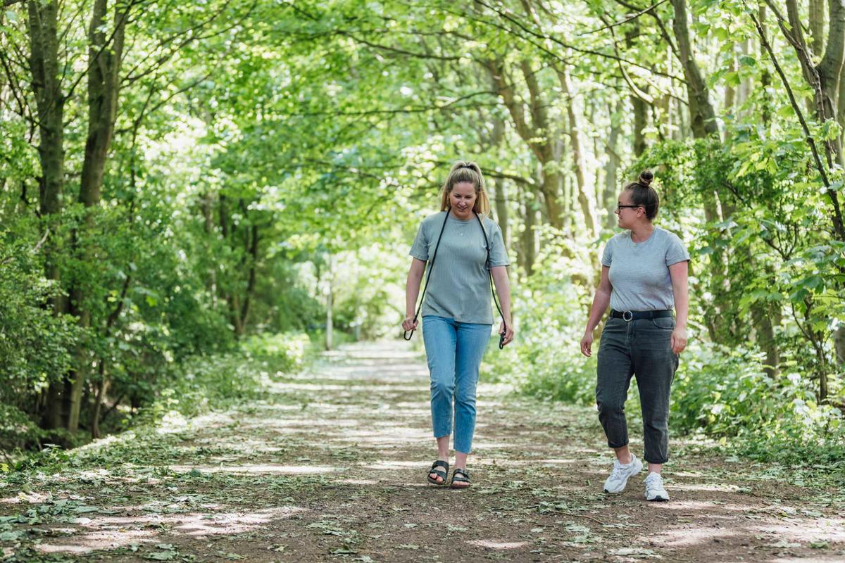 Two people talking to each other and walking on a path in woodland