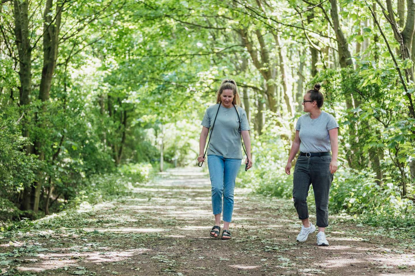 Two people talking to each other and walking on a path in woodland