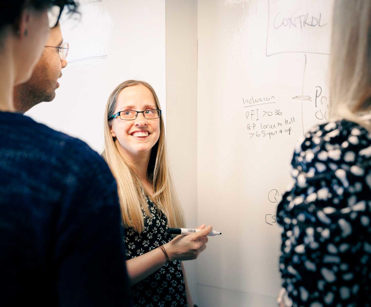 Members of the Wolfson Palliative Care Research Centre collaboratively working around a whiteboard