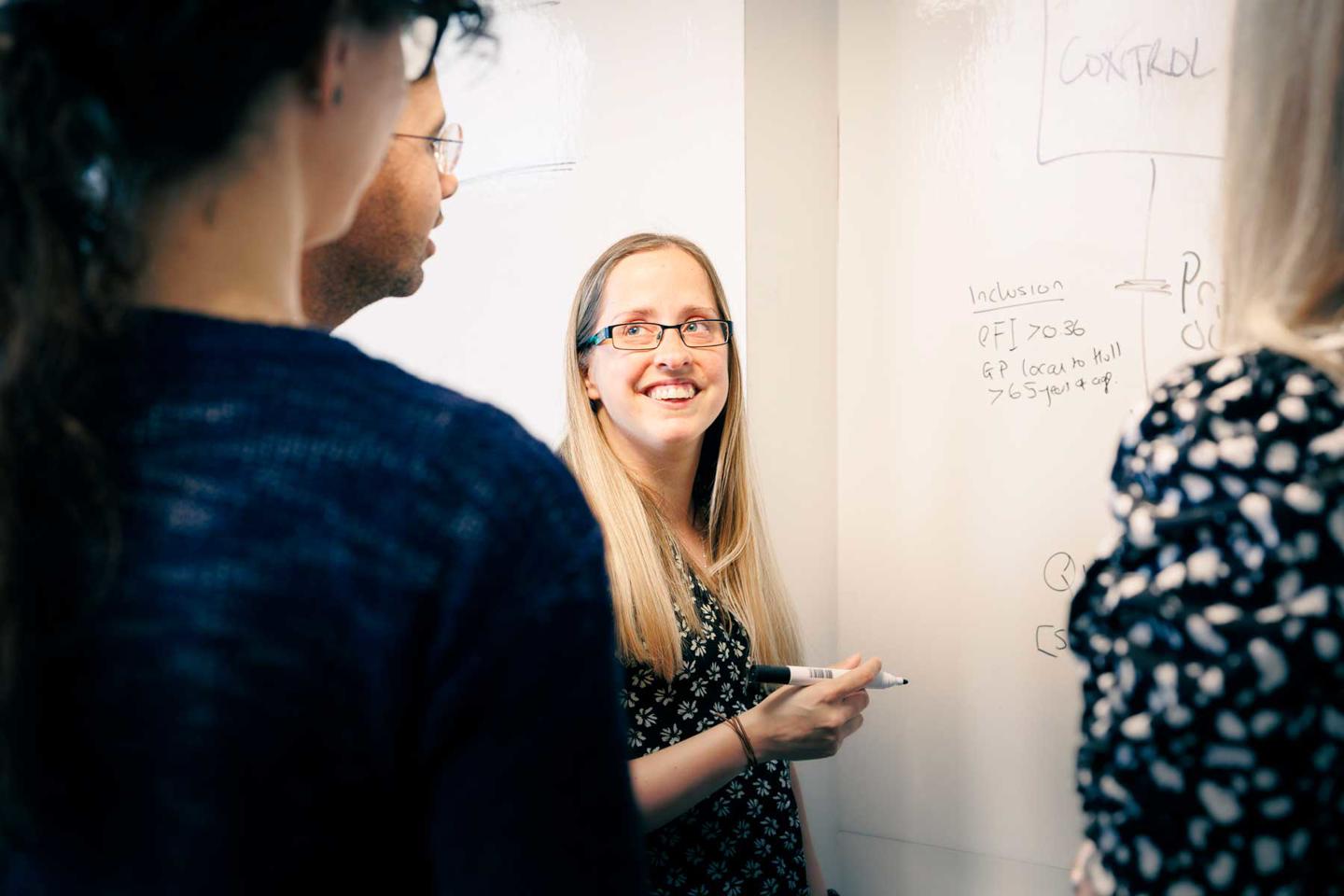 Members of the Wolfson Palliative Care Research Centre collaboratively working around a whiteboard